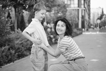 young mother and son smiling looking at the camera in modern residential complex. Having fun together, happy parenting, new home concept. Bright summer day in the urban background. High quality photo