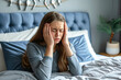 © Igor - young woman suffering from headache or migraine in bed