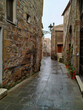 Vicolo stretto tra le case a Pitigliano con strada bagnata dalla pioggia