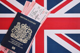 Fototapeta  - Blue British passport with airline tickets on national flag background close up. Tourism and travel concept