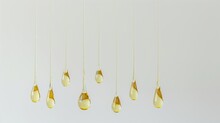 A Series Of Yellow Droplets Hanging From A White Background