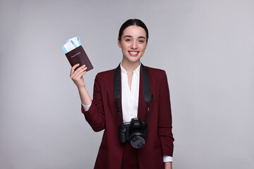 Canvas Print - Smiling businesswoman with passport, tickets and camera on grey background