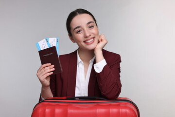 Poster - Happy businesswoman with passport, tickets and suitcase on grey background