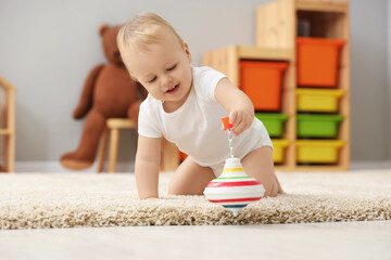 Sticker - Children toys. Cute little boy playing with spinning top on rug at home