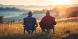 © Bonsales - Retired men sit on camp chairs against mountain landscape. Senior friends on camping vacation in nature surroundings enjoy moment of sunset.