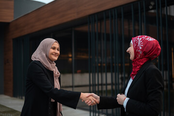 Wall Mural - Two successful business Muslim woman shaking hands finishing up meeting.