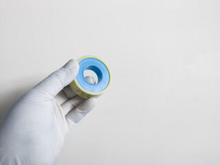 Man's hand with gloves holds a seal tape isolated on white background. Plumbing equipment concept.