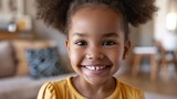 Fototapeta  - Smiling cute little African American girl with two pony tails looking at camera. Portrait of happy female child at home. Smiling face a of black 4 year old girl looking at camera with afro puff hair.