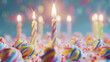 A single lit candle stands among unlit twisted candles on a colorful frosted cake with sprinkles.