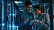 © Studio Nova - Male and a female IT professional in a data center, with the woman holding a tablet and the man observing, likely collaborating on a task.