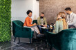 © Mediteraneo - Businesspeople working in an office lobby. Group of  businesspeople sitting together in a co-working space