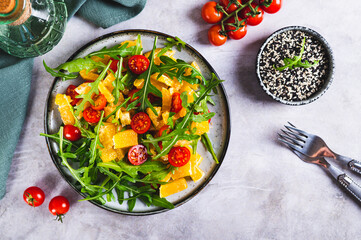 Wall Mural - Homemade salad of orange, cherry tomatoes and arugula on a plate on the table top view