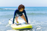Fototapeta Tematy - Young female surfer with SUP board in sea