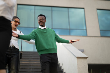 Wall Mural - Young male professional using mobile phone outside modern office building, technology and business concept.