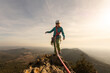 A woman is standing on a mountain top with a rope attached to her. She is wearing a helmet and a harness. Concept of adventure and excitement