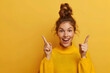 Young beautiful woman standing over yellow isolated background smiling and pointing to aside with surprise gesture.
