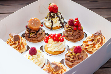 Wall Mural - Vanilla, chocolate and peanut butter cupcakes with salted caramel, fresh raspberry, strawbeery and red currant in gift paper box