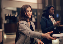 Smiling diverse businesswoman working with colleagues in the lobby of a hotel
