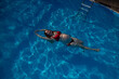 © Михаил Решетников - Top view of pregnant woman floating in pool in red bikini.