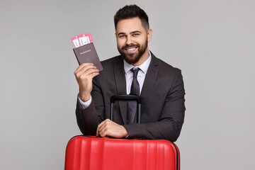 Wall Mural - Happy businessman with passport, tickets and suitcase on grey background