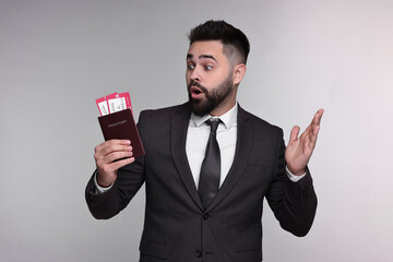 Canvas Print - Surprised businessman with passport and tickets on grey background