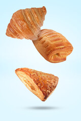 Wall Mural - Different tasty puff pastries falling on light blue background