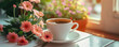 A white cup of coffee shares a sunny window sill with vibrant pink gerbera daisies, welcoming a cheerful morning.