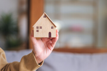 Wall Mural - Closeup image of a woman holding and showing a wooden house model