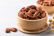 Raw peeled pecan nuts in wooden bowl on white table, Food ingredient