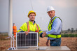 © APchanel - Engineers and manager wearing uniform holding solar call panel work cooperate hand teamwork in wind turbine farms rotation to electricity, alternative renewable energy for clean power energy concept.