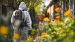 Gardener in a protective gear treats plants and flowers with pesticides against diseases and pests. Pest control spraying to obtain a large harvest.