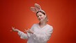 Woman in Easter bunny's ears on red background with free copy space for text of congratulation or invitation for celebrating Easter.