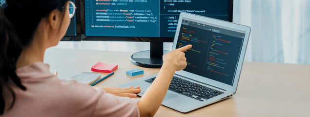 Cropped image of female web developer coding on laptop while computer displayed program and software code at modern office. Close up businesswoman hand focus on analysis data. Burgeoning.