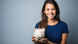 Happy young woman holding a piggybank against blue background