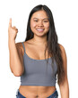© Asier - Young Chinese woman in gray top, studio showing number one with finger.