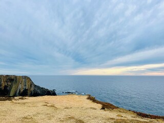 Wall Mural - Cloudy sunset at the ocean, rocky ocean coast, sunset ocean horizon, way to the ocean