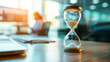 Hourglass on an office table with a blurred background, symbolizing the passage of time and productivity.