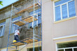 © bildlove - House facade wall renovation with new plastering and  painting. Building contractor rendering, plastering, coating walls with plaster sprayer machine or stucco concrete sprayer gun.
