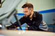 © bnenin - Mechanic man fixing a car, dressed in a uniform, in his garage.