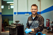 © bnenin - A smiling mechanic man is standing in his garage, posing for the camera.