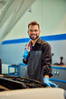 © bnenin - A mechanic working in his car repair service, holding a cloth, smiling for the camera.