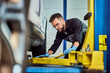 © bnenin - A mechanic working on the car fixing, using a machine for car lifting.