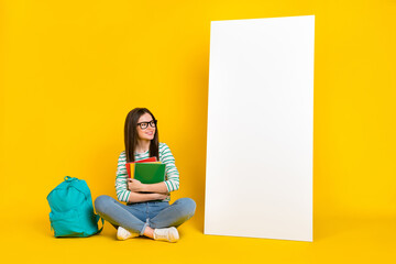 Wall Mural - Photo of sitting female college student with homework materials look white banner placard isolated on yellow color background