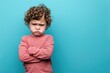 Angry disgruntled little boy on a solid blue background