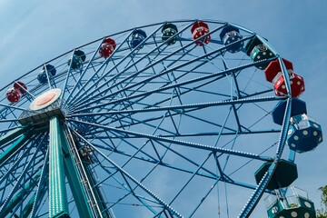 Colorful ride ferris wheel in motion in amusement park on sky background.