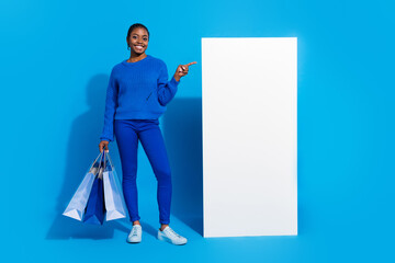 Wall Mural - Full length body size view of attractive trendy girl holding bags showing copy space ad isolated over bright blue color background