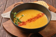 pumpkin carrot soup in a black bowl on a wooden table