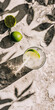 Mobile vertical wallpaper top view of a gin tonic sparkling cocktail with lime on a concrete floor. Sunshine. . Story post.