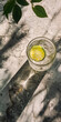 Mobile vertical wallpaper top view of a gin tonic sparkling cocktail with lime on a concrete floor. Sunshine. . Story post.