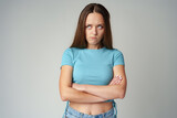 Fototapeta Na sufit - Portrait of sad displeased offended young woman in blue T-shirt on gray background